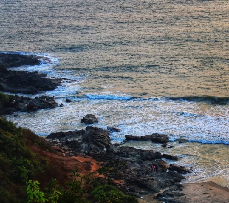 A scenic view of Apsarakonda Beach showing the meeting point of lush green hills, sandy shore, and the Arabian Sea