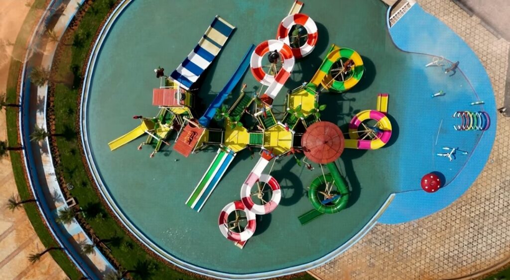 Top aerial view of Joy and Joyy Waterpark showing colorful slides, large pools, and surrounding greenery.