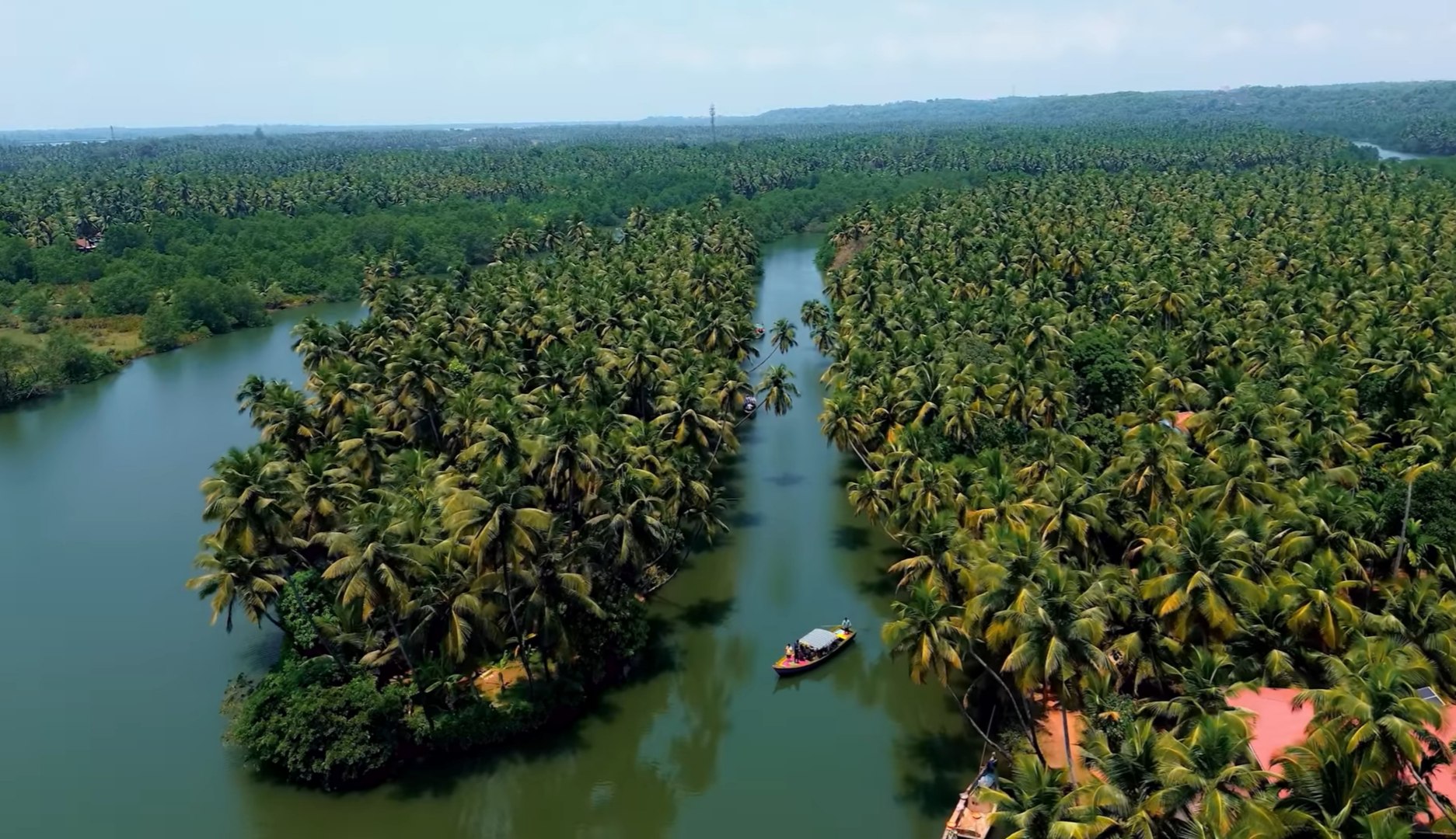 Wide shot of a boat gliding through calm Sharavathi backwaters.